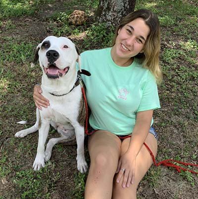 dog-boarding-in-davie Dog sitter is sitting on the grass with her large size dog.