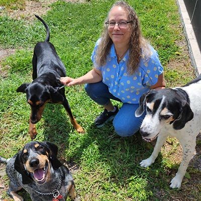 dog-sitter-in-coral-springs A dog sitter in Coral Spring is playing with 3 dogs in the yard.