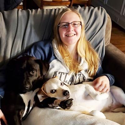 pet-sitter-in-cooper-city Pet sitter is sitting on the sofa with 2 dogs.