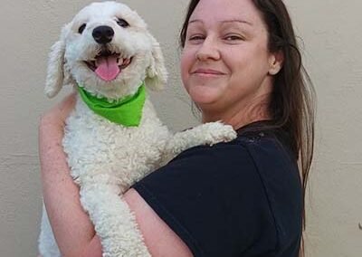 Pet sitter is holding a white dog.