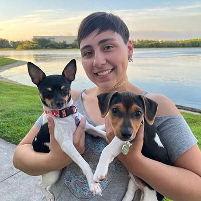 pet-sitter-in-pembroke-pines Pet sitter is holding two dogs in the front of a lake.